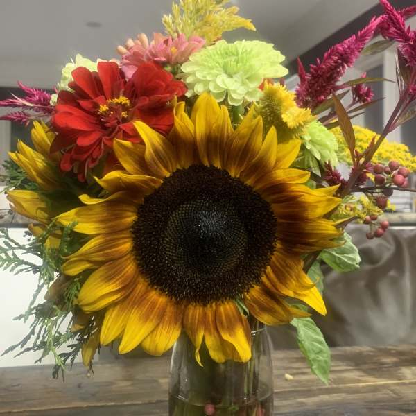 Sunflower bouquet in a glass vase with red, pink, and yellow flowers