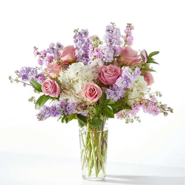 Pink roses and lavender flowers arranged in a clear glass vase