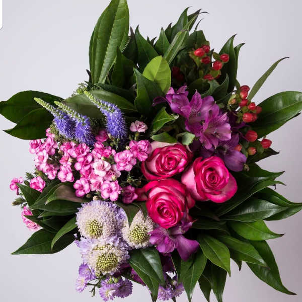 Bouquet of pink roses, purple flowers, and glossy greenery