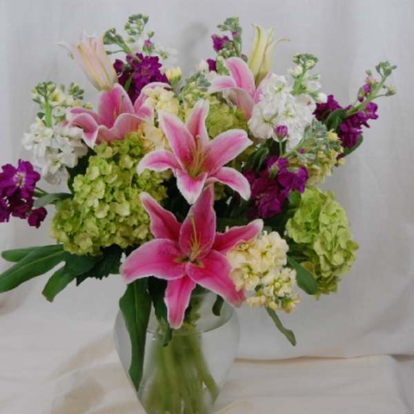 Pink lilies and mixed blooms in a clear glass vase