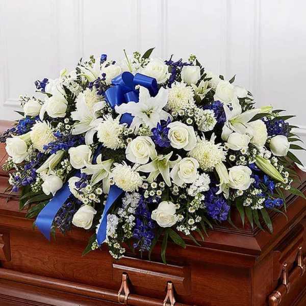 White and blue floral spray on a wooden casket