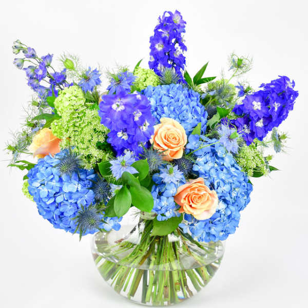 Blue and peach flower arrangement in a clear glass vase