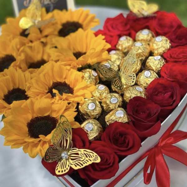 Heart-shaped box with sunflowers, red roses, and gold-wrapped chocolates