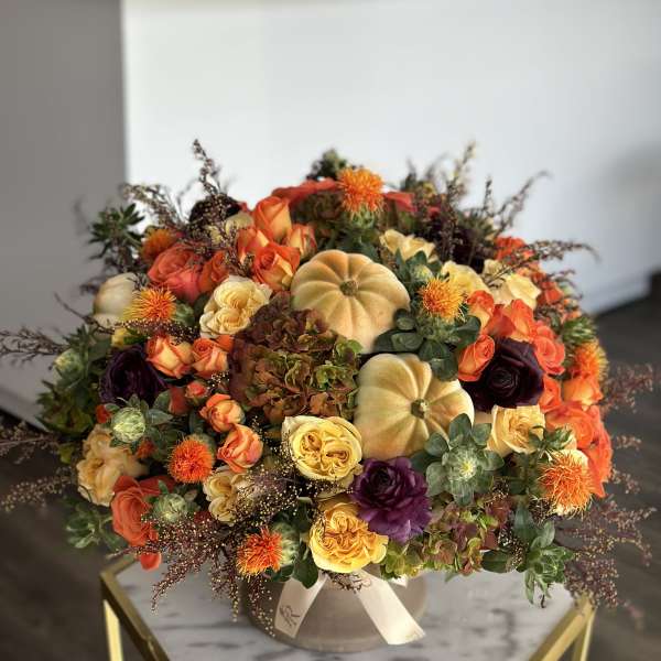 Large floral arrangement with orange, yellow, and purple blooms in a vase