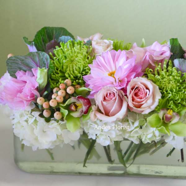 Pink and green floral arrangement in a clear rectangular vase
