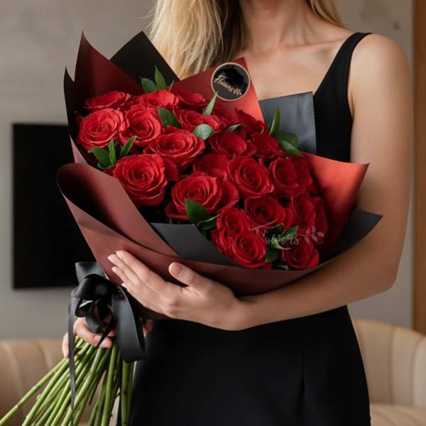 Bouquet of red roses wrapped in dark paper