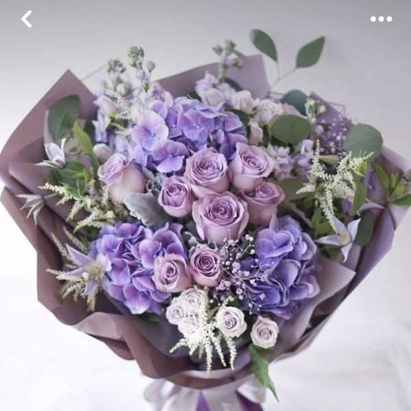 Lavender and purple bouquet of roses and hydrangeas wrapped in mauve paper