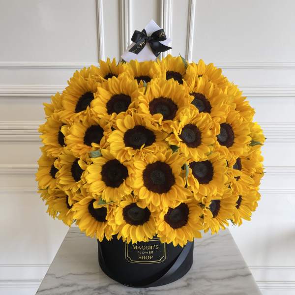 Large bouquet of yellow sunflowers in a black hatbox with a ribbon