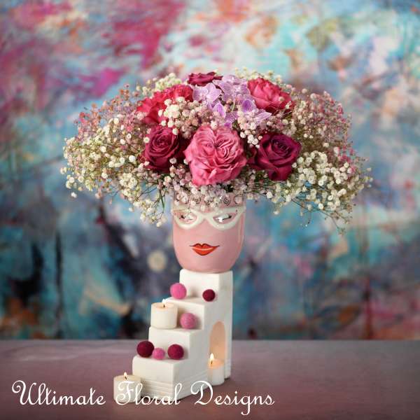 Pink and magenta roses with baby's breath in a decorative vase