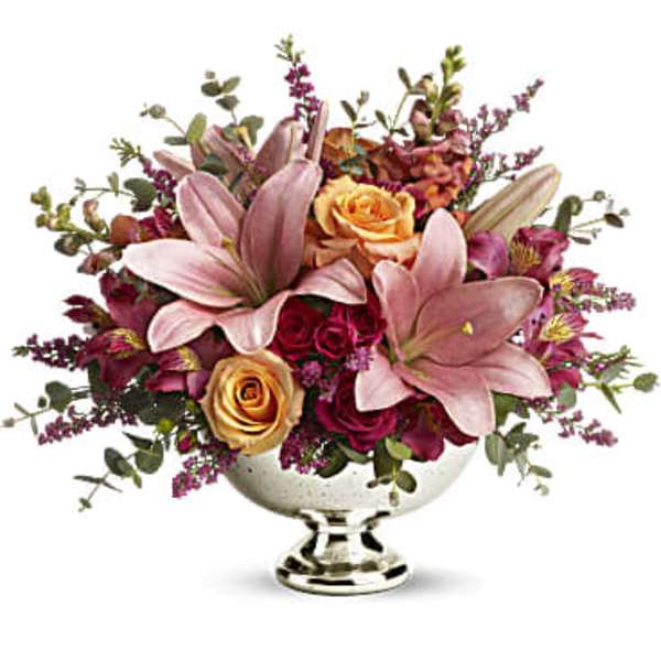 Pink lilies and roses arranged in a silver pedestal bowl