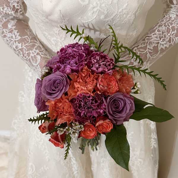 Bride holding a bouquet of purple and coral flowers