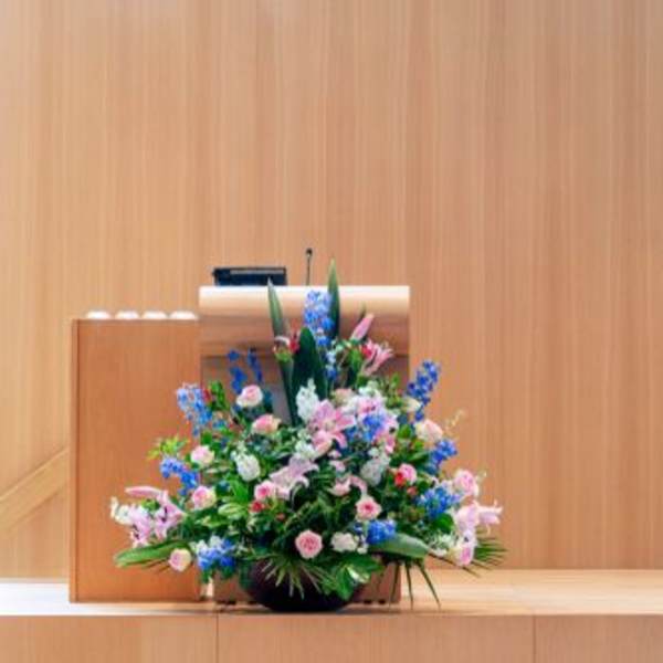 Large mixed floral arrangement in pink, blue, and white on a stage podium