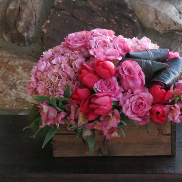 Pink floral arrangement in a wooden box with roses and hydrangeas