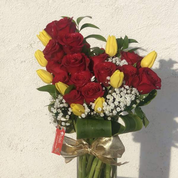 Bouquet of red roses and yellow tulips in a glass vase