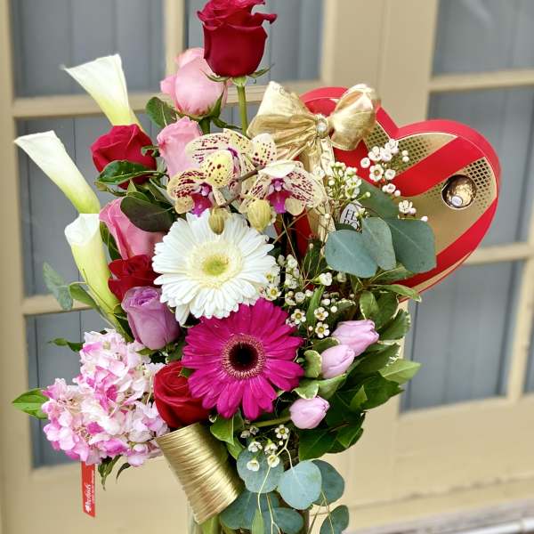Mixed bouquet in a glass vase with roses, gerbera daisies, orchids, and calla lilies