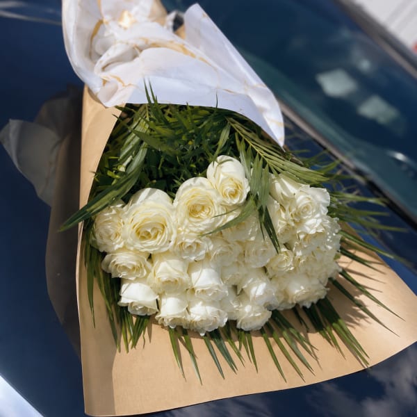 Bouquet of white roses wrapped in brown and white paper