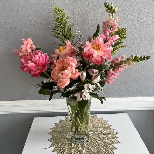 Pink and peach flowers arranged in a clear glass vase