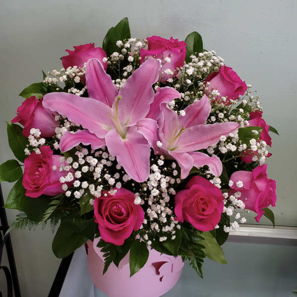 Pink lilies and roses in a pink hatbox with baby's breath