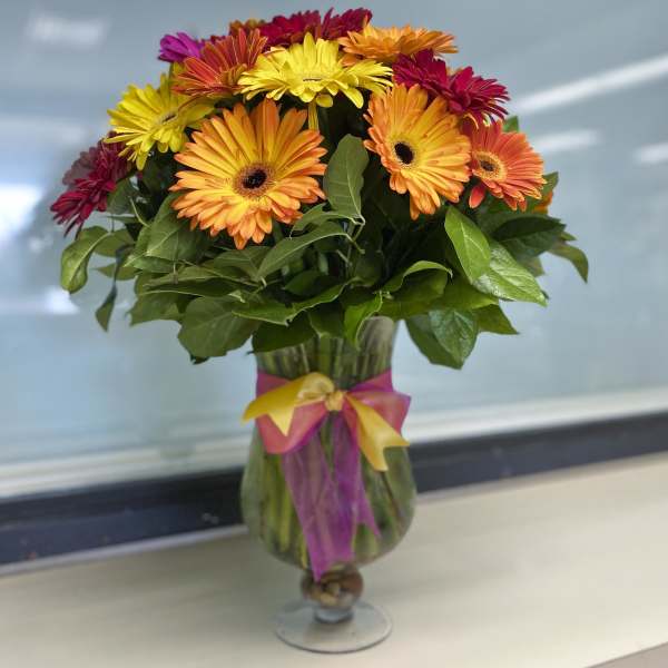 Colorful gerbera daisy bouquet in a glass vase with ribbon