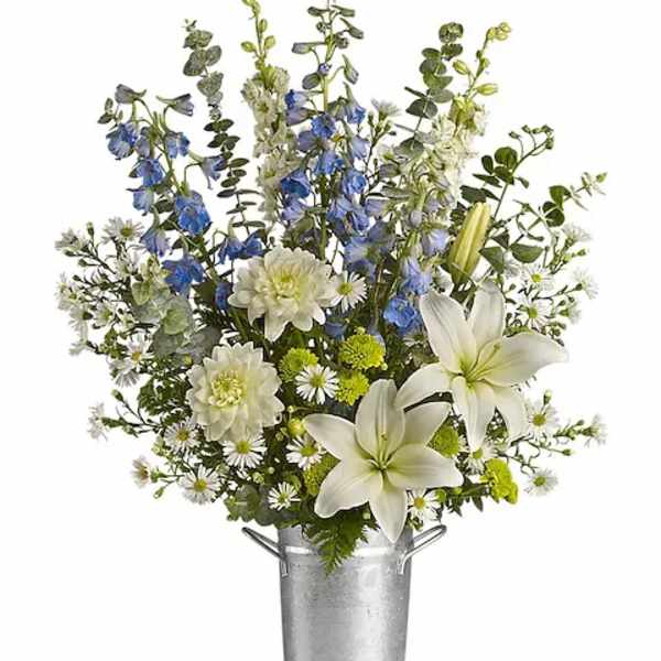 White lilies and blue flowers in a tall metal bucket