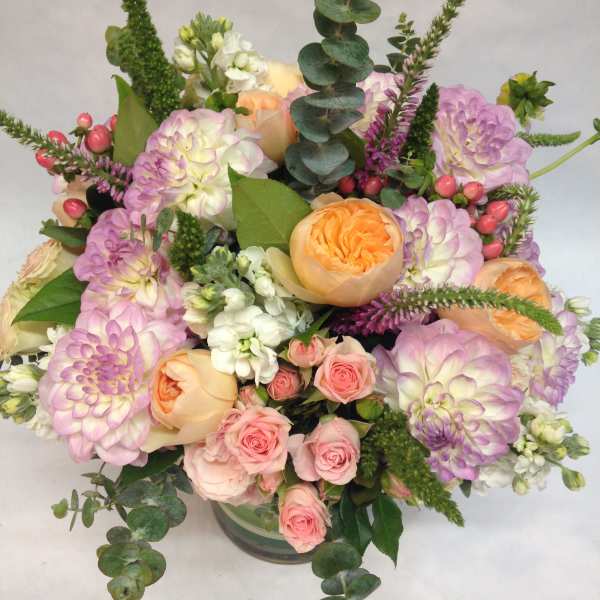 Pastel bouquet of roses, dahlias, and white blooms in a glass vase