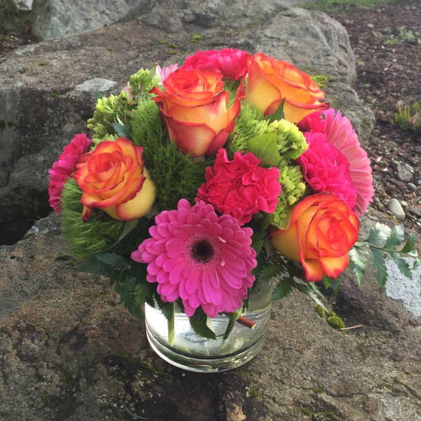 Bright mixed bouquet of roses and gerbera daisies in a glass vase
