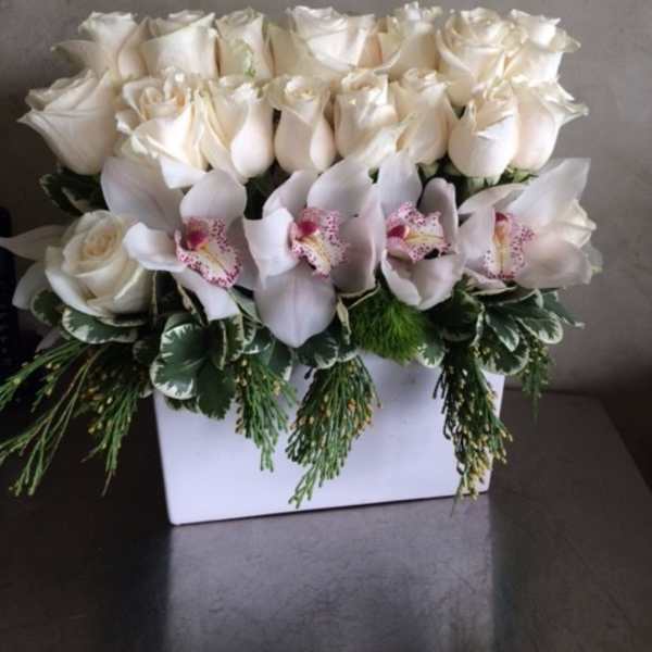 White roses and pale orchids arranged in a white box