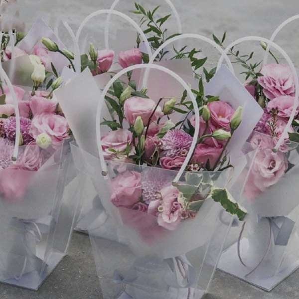 Pink flower bouquets in clear gift bags with white handles