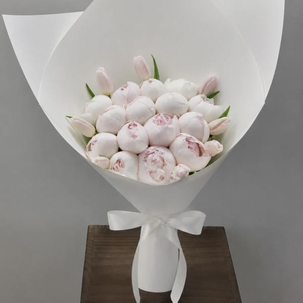 Bouquet of pale pink peonies and tulips wrapped in white paper