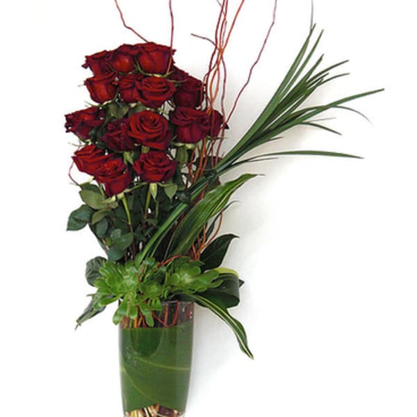 Tall vase arrangement of red roses with decorative grass