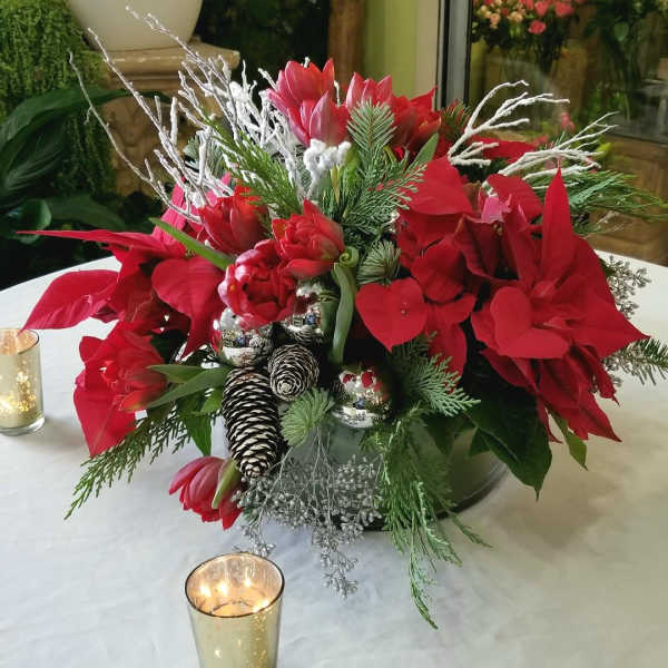 Red holiday floral arrangement with pinecones and silver ornaments in a vase