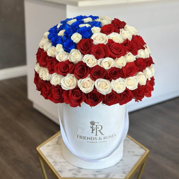 Large round bouquet of red, white, and blue roses in a white hat box