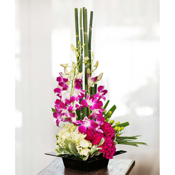 Tall floral arrangement with pink orchids and hydrangeas in a black square vase