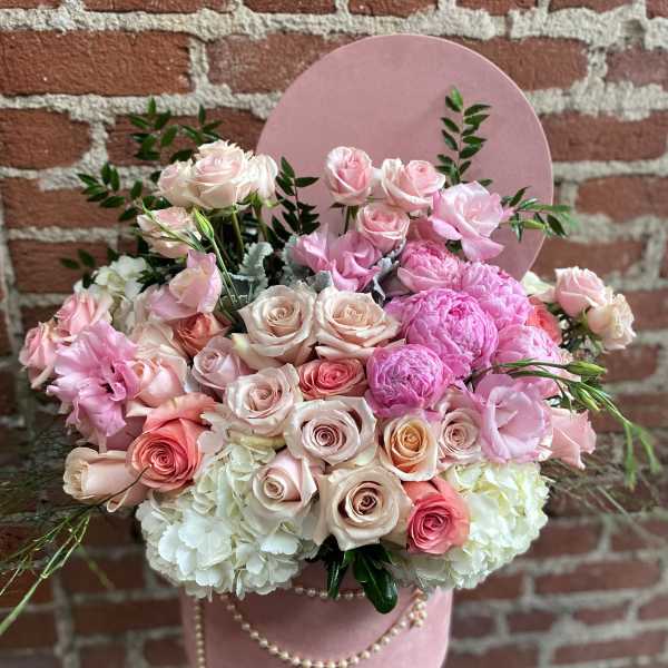 Pink and white flower arrangement with roses and peonies in a pink hatbox