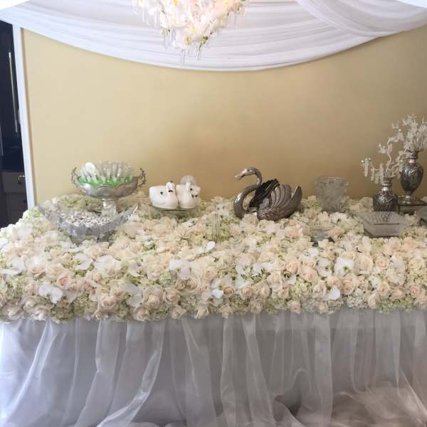 Large table covered in white and blush roses with silver decor pieces