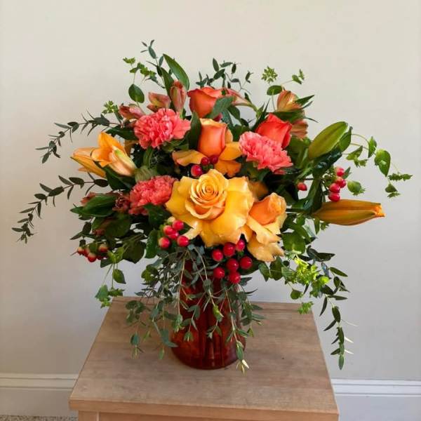 Orange and pink floral arrangement in a red vase
