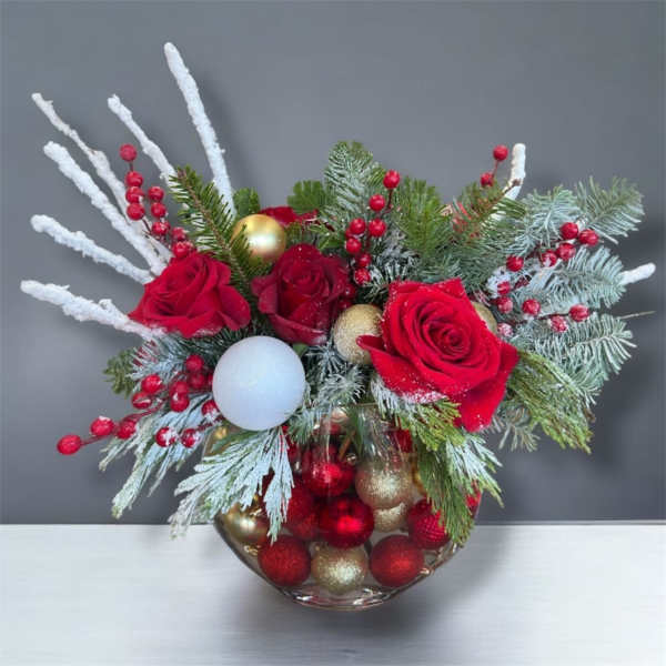 Red roses in a glass bowl with pine, berries, and ornaments