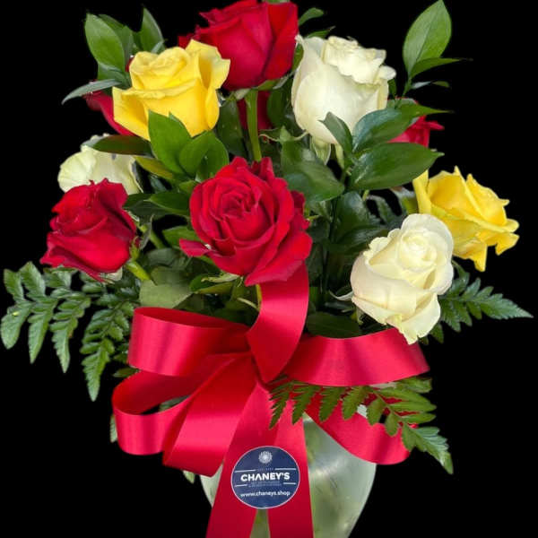 Bouquet of red, yellow, and white roses in a glass vase with a red ribbon