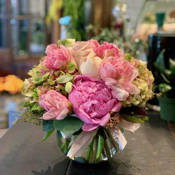 Pink peonies and roses arranged in a clear glass vase