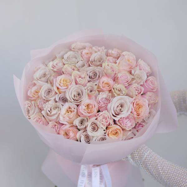 Bouquet of pale pink and cream roses wrapped in pink paper