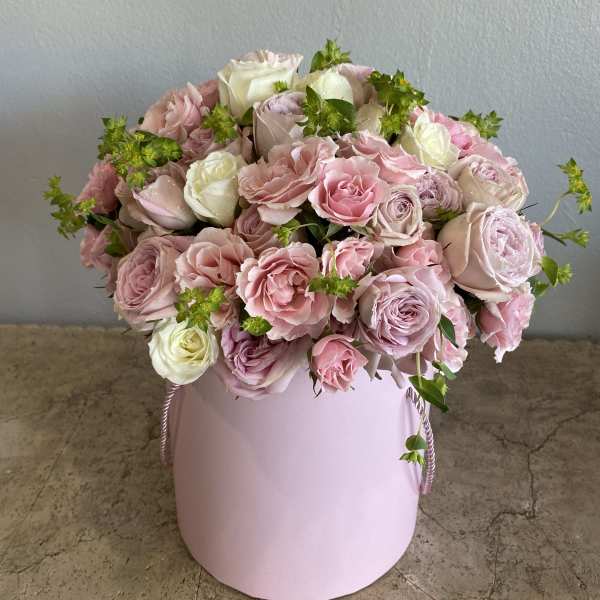 Pink and white roses arranged in a round pastel pink box