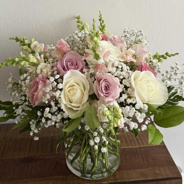 Pink and white roses with baby's breath in a clear glass vase