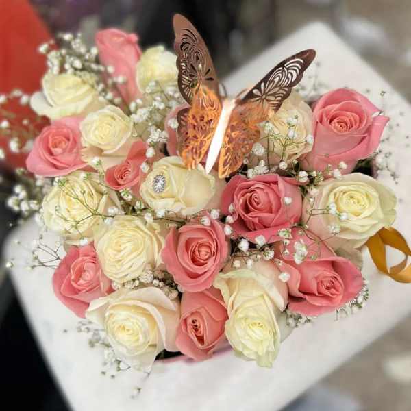 Pink and white roses arranged with baby's breath and a butterfly topper