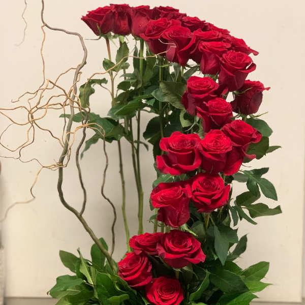 Tall arrangement of red roses in a textured gray container