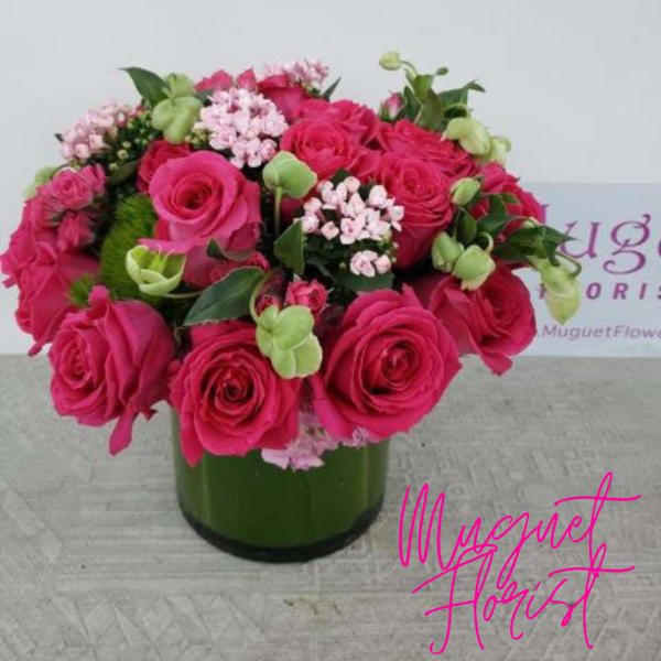 Pink roses and small pale pink flowers arranged in a green glass vase