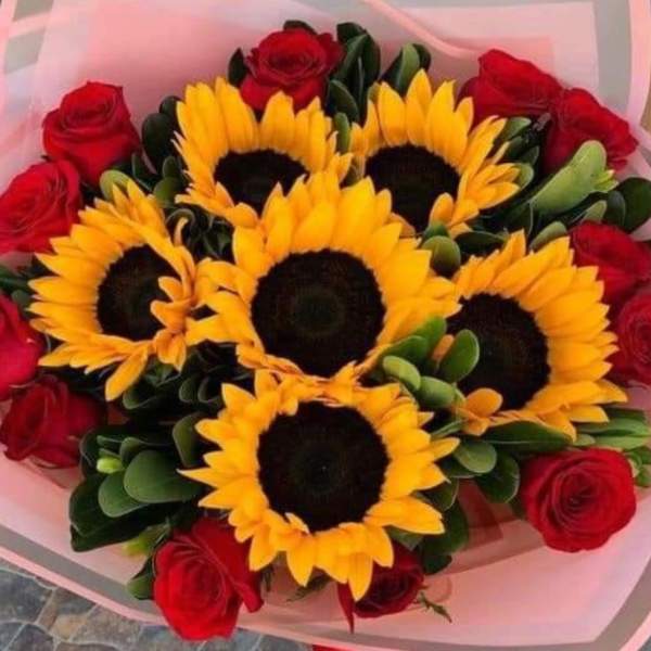 Bouquet of sunflowers and red roses wrapped in pink paper
