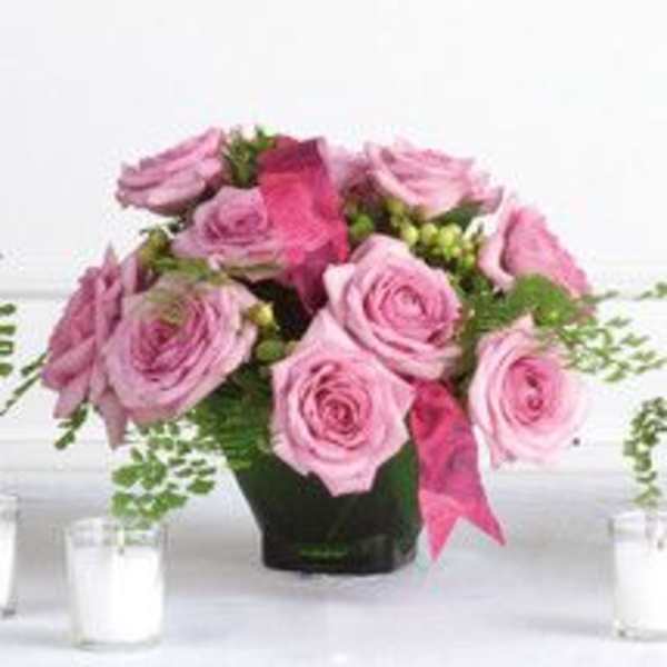 Pink roses arranged in a dark vase with trailing greenery