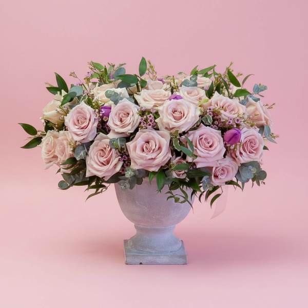 Pink and white roses arranged in a pedestal vase
