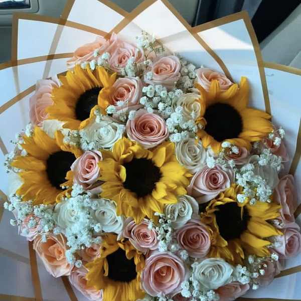 Bouquet of sunflowers and pastel roses wrapped in white paper