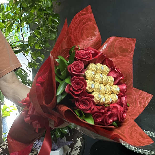 Bouquet of red roses with gold-wrapped chocolates in red wrapping